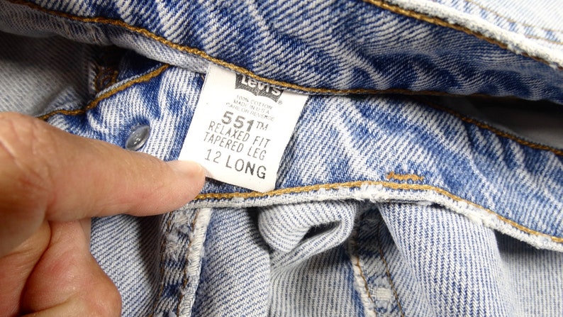 K&ouml;nnte beinhalten: Nahaufnahme eines blauen Jeans-Etiketts von Levi's 551&trade; Relaxed Fit Tapered Leg mit der Gr&ouml;&szlig;e 12 Long.