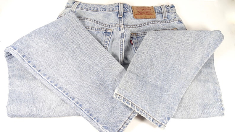 K&ouml;nnte beinhalten: Eine hellblaue Jeanshose, die in der H&auml;lfte gefaltet ist. Die Jeans hat ein braunes Leder-Etikett auf der R&uuml;ckseite mit dem Text "Levi's&reg; Original  Quality  Guaranteed  501&reg;  Made in the USA  W 32 L 34".