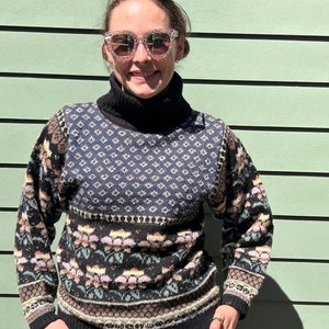 May include: A black and white patterned turtleneck sweater with a floral design. The sweater has a mock neck and long sleeves.