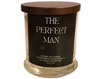May include: A clear glass candle jar with a dark brown lid. The label reads "THE PERFECT MAN" in white text on a black background. The candle is a natural soy candle, hand-poured in Jacksonville, FL, with a 60-hour burn time and 12 fl oz.
