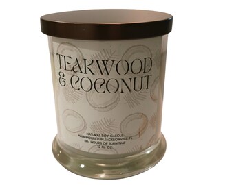 May include: A clear glass jar candle with a bronze lid. The label reads "TEAKWOOD & COCONUT" with a coconut pattern. It is a natural soy candle, hand-poured in Jacksonville, FL, with a 60-hour burn time and 12 fl oz.