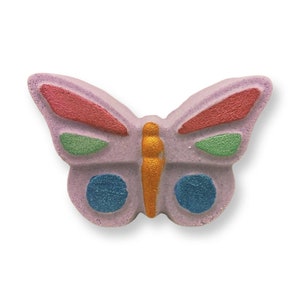 Puede incluir: Una bomba de baño con forma de mariposa en tonos lavanda, rojo, verde, azul y dorado. Las alas tienen detalles rojos y verdes, con círculos azules en las alas inferiores. El cuerpo es dorado.