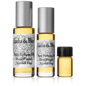 May include: Three glass bottles of perfume oil with silver caps. The bottles are labeled "Lulu & Bee Pure Perfume Oil Hand Poured Alcohol Free".