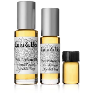 May include: Three glass bottles of perfume oil with silver and black caps. The bottles are labeled "Lulu & Bee Pure Perfume Oil Hand Poured Alcohol Free".