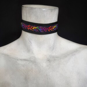 May include: A black choker necklace with a rainbow flame design.