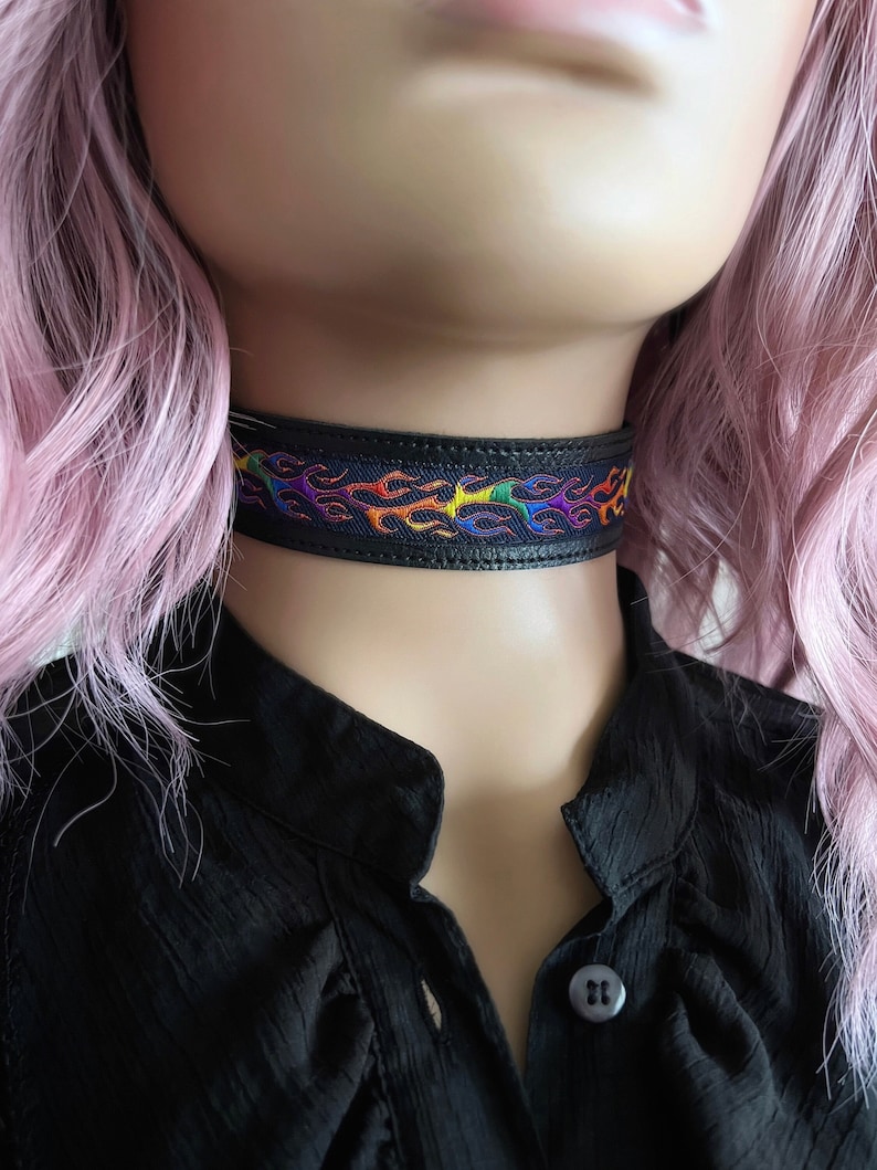 Rainbow flame print jacquard ribbon upper sewn onto a one inch wide black faux vegan leather choker collar base. Piece is adjustable and closes in back with a black metal hook. Tags lgbtq pride month queer gay goth flamer ribbon necklace punk rock