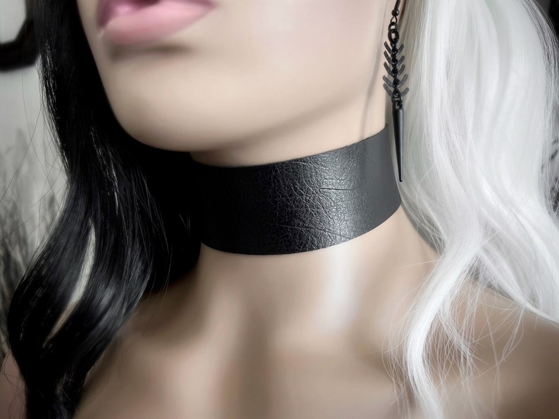 One and a half inch extra wide black vegan leather choker collar necklace. Piece closes in back with black metal nylon coated hook and is fully adjustable with a black metal nylon coated slider. Tags goth punk sexy dark fashion jewelry faux leather