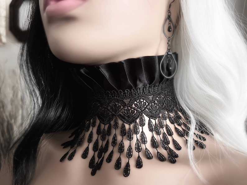 May include: A black lace choker with a ruffled satin collar. The choker has a delicate fringe of teardrop-shaped lace.