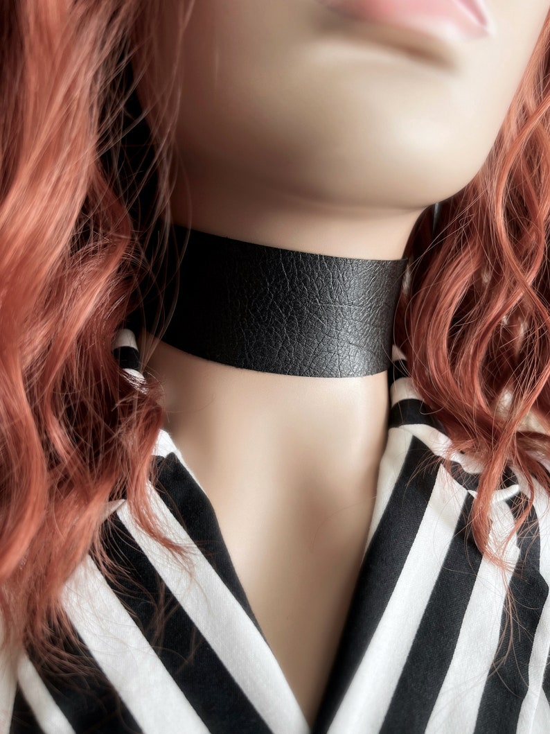 One and a half inch extra wide black vegan leather choker collar necklace. Piece closes in back with black metal nylon coated hook and is fully adjustable with a black metal nylon coated slider. Tags goth punk sexy dark fashion jewelry faux leather