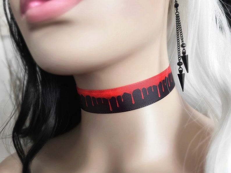 May include: Black choker necklace with a red dripping blood design.