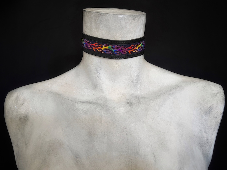 May include: A black choker necklace with a rainbow flame design.