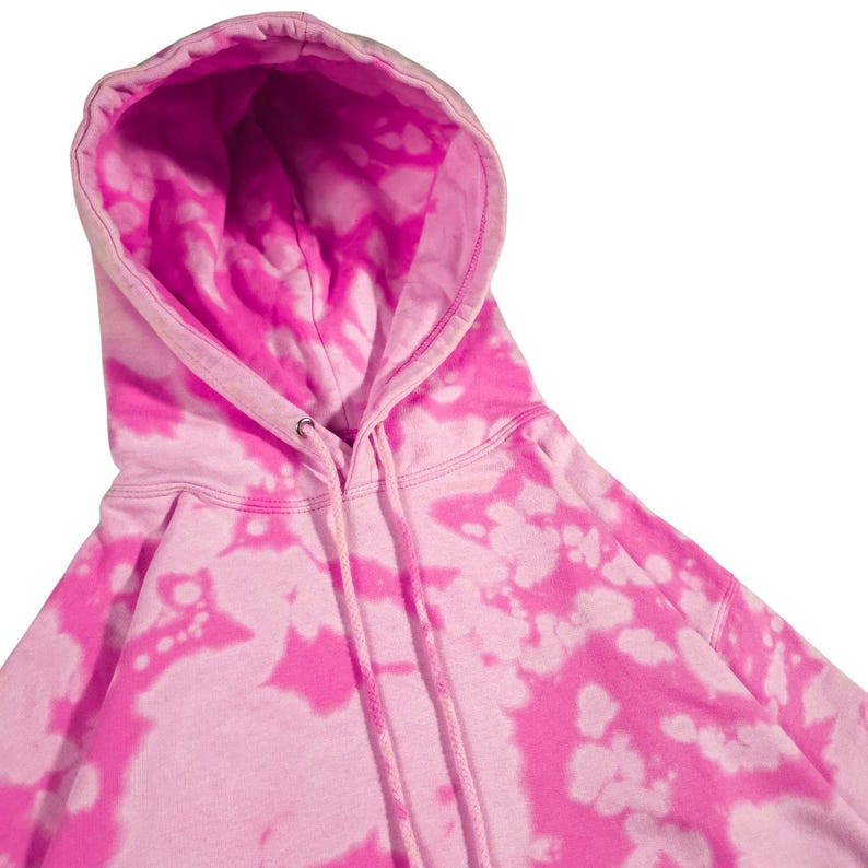 Puede incluir: Una sudadera con capucha rosa te&ntilde;ida con un cord&oacute;n. La sudadera con capucha presenta un vibrante patr&oacute;n rosa y blanco, con el interior de la capucha de color rosa liso. La prenda est&aacute; hecha de un material suave.