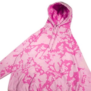Puede incluir: Una sudadera con capucha rosa te&ntilde;ida con un bolsillo de canguro y una capucha con cord&oacute;n. La sudadera con capucha presenta un vibrante patr&oacute;n rosa y blanco, creando un aspecto &uacute;nico y elegante. Esta sudadera informal es perfecta para el uso diario.