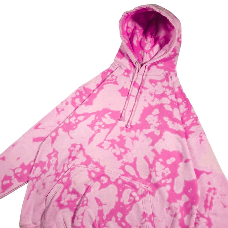 Puede incluir: Una sudadera con capucha rosa te&ntilde;ida con un bolsillo de canguro y una capucha con cord&oacute;n. La sudadera con capucha presenta un vibrante patr&oacute;n rosa y blanco, creando un aspecto &uacute;nico y elegante. Esta sudadera informal es perfecta para el uso diario.