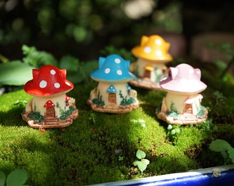May include: Four miniature mushroom houses with white polka dots. The houses are painted in red, blue, yellow, and pink. The houses are sitting on a bed of green moss.