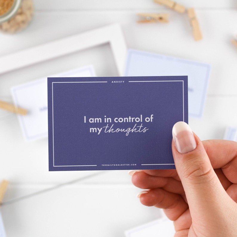 K&ouml;nnte beinhalten: Eine violette Affirmationskarte mit wei&szlig;em Text, der "Ich habe meine Gedanken unter Kontrolle." lautet. Die Karte tr&auml;gt den Text "ANXIETY" oben rechts und "THEDAILYGOALGETTER.COM" unten rechts.