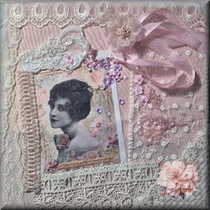 May include: A textile collage featuring a black and white portrait of a person surrounded by pink fabric, white lace trim, and sheer floral overlays. The composition includes pink ribbon, iridescent sequins, pearl-like beads, and fabric flowers.