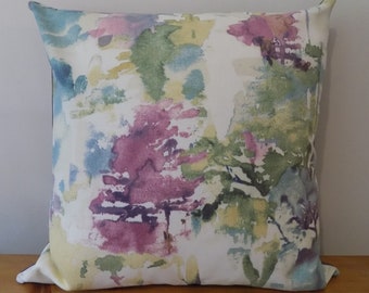 May include: A white throw pillow with a watercolor-style print of abstract shapes in shades of pink, green, blue, and yellow.