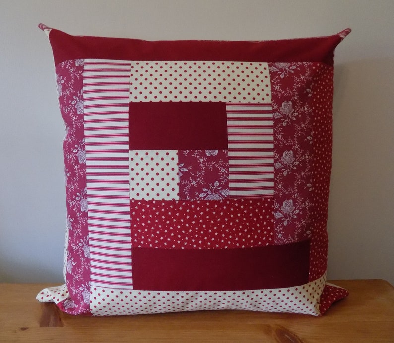 Puede incluir: Funda de coj&iacute;n de patchwork rojo, blanco y crema con un patr&oacute;n floral. La funda de coj&iacute;n est&aacute; hecha de diferentes telas con varios patrones, incluyendo lunares, rayas y dise&ntilde;os florales.