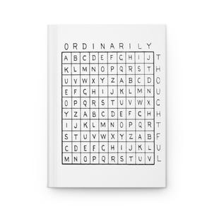 Puede incluir: Un cuaderno blanco con la palabra "ORDINARILY" en la parte superior. Debajo, una cuadrícula de letras, similar a un juego de búsqueda de palabras. El cuaderno está cerrado y tiene un diseño limpio y minimalista.