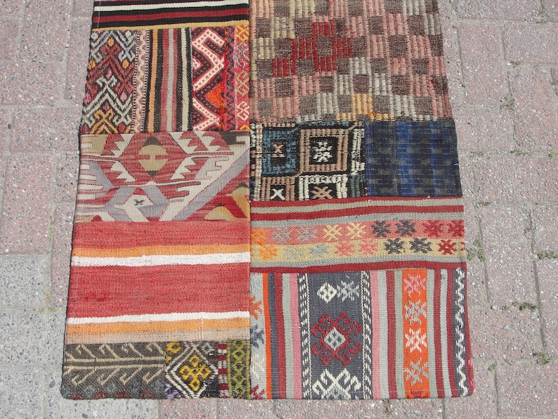 May include: A patchwork rug with a variety of colorful geometric patterns and designs. The rug is made of wool and has a hand-woven texture.