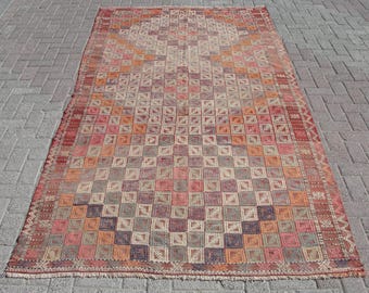May include: A vintage Turkish rug with a geometric pattern in shades of red, orange, beige, and brown. The rug has a checkered design with a central medallion.