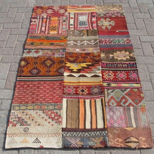 May include: A patchwork rug with a variety of colors and patterns, including red, orange, brown, and white. The rug is made of wool and has a hand-woven texture.