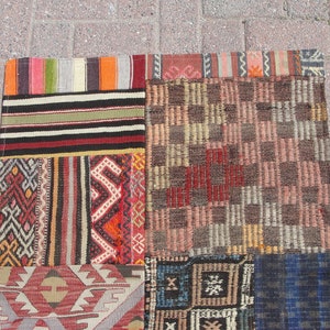 May include: A patchwork rug with a variety of colorful patterns and designs. The rug is made up of several different pieces of fabric that have been sewn together. The rug is a mix of red, blue, green, yellow, and brown colors.
