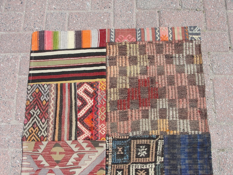 May include: A patchwork rug with a variety of colorful patterns and designs. The rug is made up of several different pieces of fabric that have been sewn together. The rug is a mix of red, blue, green, yellow, and brown colors.