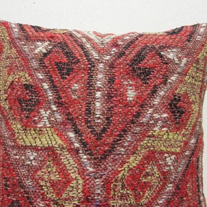 May include: A red, black, and gold patterned throw pillow with a geometric design. The pillow is made of a woven fabric and has a soft, textured surface.