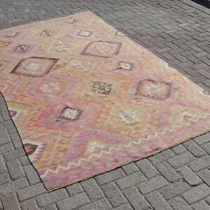 K&ouml;nnte beinhalten: Ein antiker t&uuml;rkischer Teppich mit einem geometrischen Muster in Rosa-, Orange- und Beiget&ouml;nen. Der Teppich hat einen abgenutzten und verblassten Look, der ihm ein rustikales und antikes Aussehen verleiht.