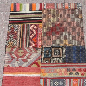 May include: A patchwork rug with a variety of colorful geometric patterns and stripes. The rug is made of wool and has a hand-woven texture.