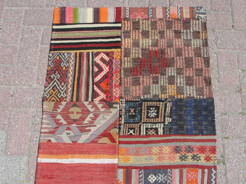 May include: A patchwork rug with a variety of colorful geometric patterns and stripes. The rug is made of wool and has a hand-woven texture.