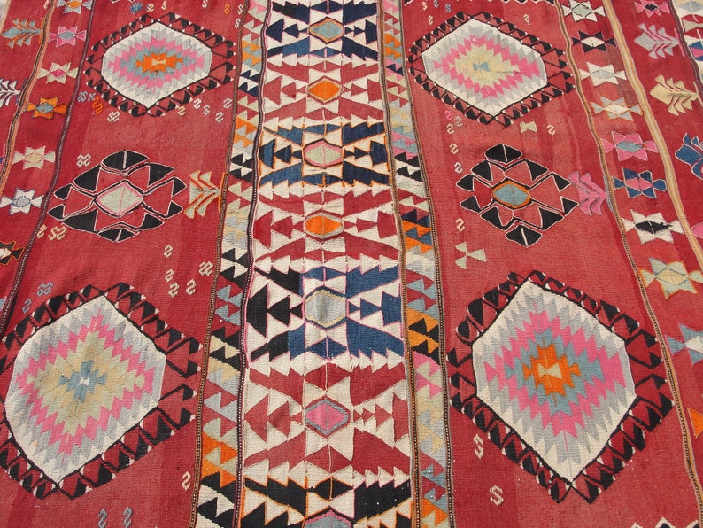 May include: A red, white, blue, and orange patterned rug with a geometric design. The rug has a traditional Turkish kilim style.