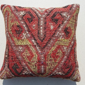 May include: Red, black, and white patterned throw pillow with a geometric design. The pillow is made of woven fabric and has a square shape.
