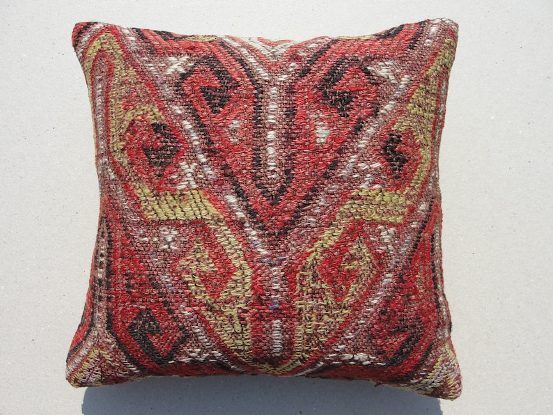 May include: Red, black, and white patterned throw pillow with a geometric design. The pillow is made of woven fabric and has a square shape.