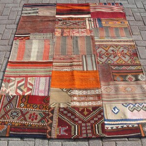 May include: A colorful patchwork rug with various shades of red, orange, brown, and white. The rug is made of woven fabric and has a geometric pattern.