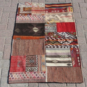 Peut inclure: Un tapis patchwork avec une variété de couleurs et de motifs, notamment rouge, marron, blanc et noir. Le tapis est composé de différents morceaux de tissu cousus ensemble.