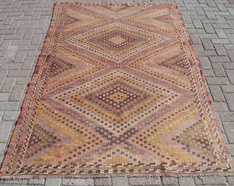 May include: A vintage rug with a geometric pattern in shades of brown, red, and yellow. The rug has a diamond-shaped design with a central diamond and a border.