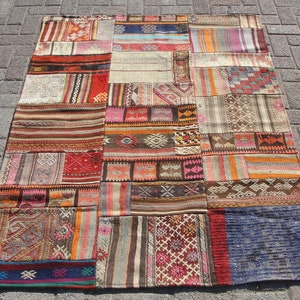 Può includere: Un tappeto patchwork colorato con una varietà di motivi e colori, tra cui rosso, arancione, giallo, verde, blu e marrone. Il tappeto è realizzato in tessuto tessuto e ha un bordo con frange.