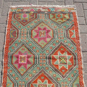 Puede incluir: Una alfombra colorida con un patr&oacute;n geom&eacute;trico en tonos rojos, verdes, naranjas y rosas. La alfombra tiene un borde de flecos.