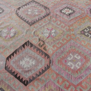 K&ouml;nnte beinhalten: Ein antiker t&uuml;rkischer Teppich mit einem geometrischen Muster in Rosa-, Grau- und Schwarzt&ouml;nen. Der Teppich hat einen abgenutzten Look und ist mit komplizierten Details gewebt.