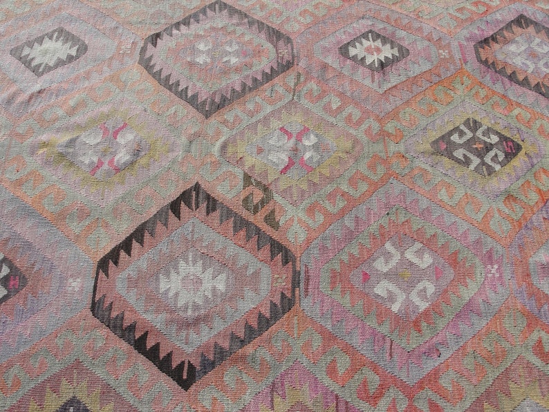 K&ouml;nnte beinhalten: Ein antiker t&uuml;rkischer Teppich mit einem geometrischen Muster in Rosa-, Grau- und Schwarzt&ouml;nen. Der Teppich hat einen abgenutzten Look und ist mit komplizierten Details gewebt.