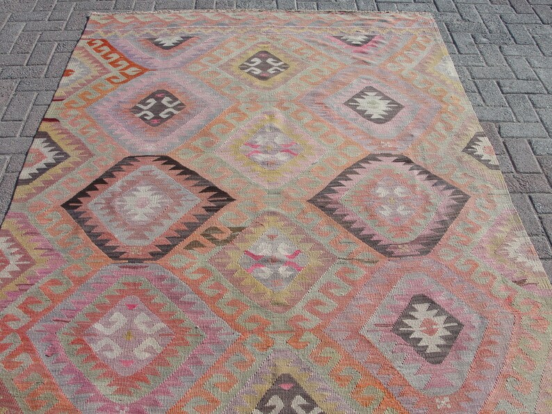 K&ouml;nnte beinhalten: Ein antiker t&uuml;rkischer Teppich mit einem geometrischen Muster in Rosa-, Orange-, Braun- und Beiget&ouml;nen. Der Teppich hat ein rautenf&ouml;rmiges Design mit komplizierten Details.