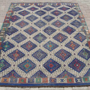 May include: A large, rectangular rug with a repeating diamond pattern. The diamonds are primarily blue, with accents of red, green, and orange. The background is a neutral beige color, and the border is a darker blue with decorative elements.