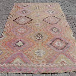 K&ouml;nnte beinhalten: Ein antiker t&uuml;rkischer Teppich mit einem geometrischen Muster in Rosa-, Orange- und Braunt&ouml;nen. Der Teppich hat einen verblassten, abgenutzten Look, der ihm ein rustikales und antikes Aussehen verleiht.
