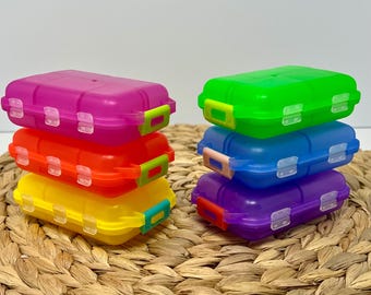 May include: Two stacks of three rectangular plastic storage containers with hinged lids and snap closures. The left stack features magenta, orange, and yellow containers. The right stack features green, blue, and purple translucent containers.