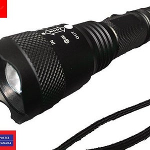 Op de afbeelding: Een zwarte zaklamp met zoomfunctie. De zaklamp heeft een getextureerde grip en een zwarte koord.