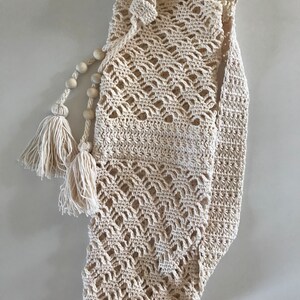 May include: A cream-colored crocheted yoga mat bag with wooden beads and tassels.