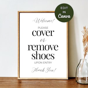 May include: A framed sign with a wooden frame and white background. The sign reads "Welcome! Please cover or remove shoes upon entry. Thank You!" in elegant black script. A green circle with "Edit in Canva" is in the upper right corner.